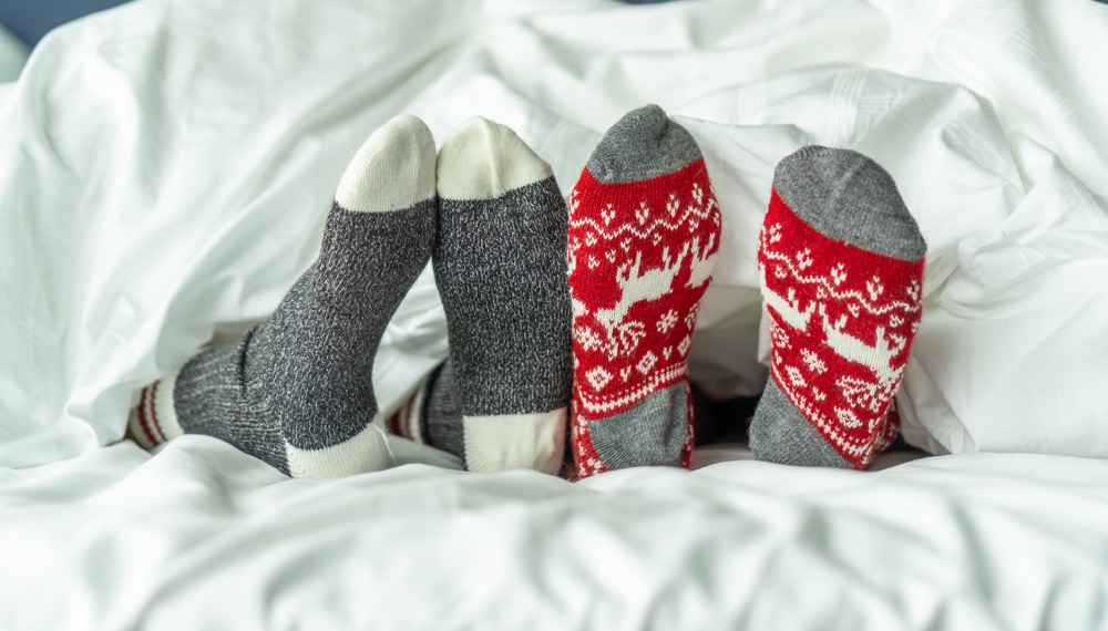 feet with holiday socks poking out of bedsheets