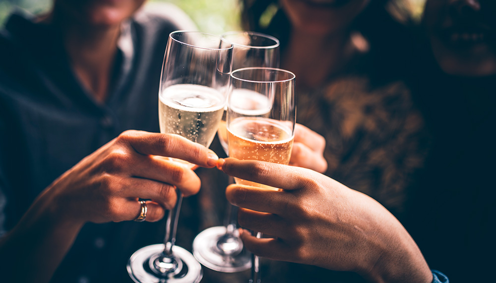 3 Hands do a cheers with glasses of sparkling wine