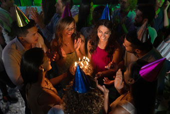 woman is presented with a birthday cake at a crowded party