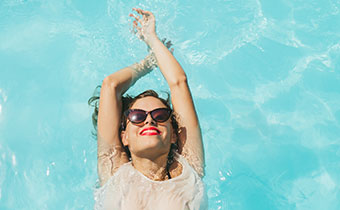 Woman floating in pool with sunglasses
